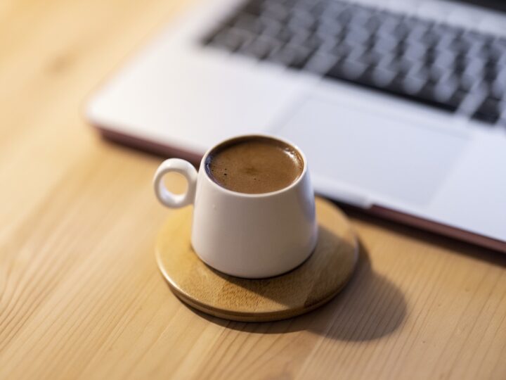 shot of espresso in a cup by a laptop computer