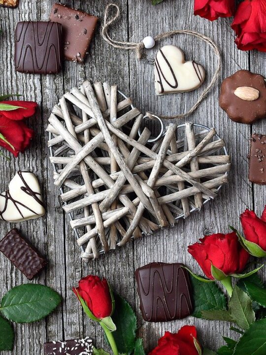 chocolates, roses and a heart laid out on a grey board