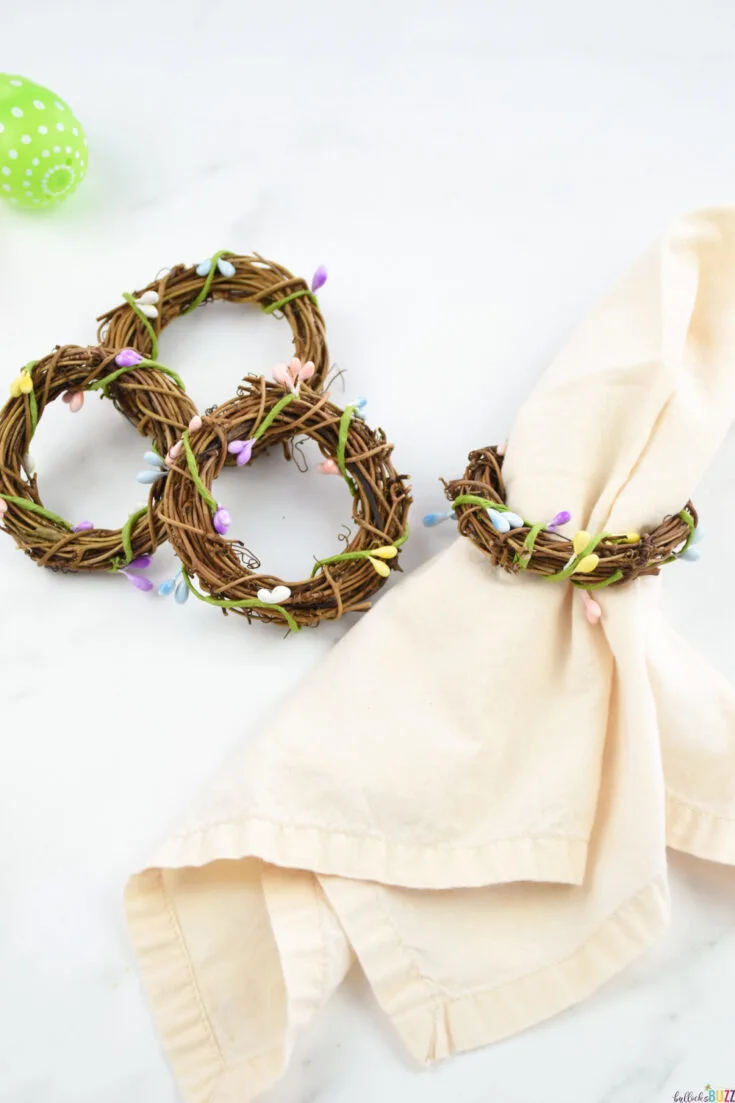 3 DIY Easter Napkin Rings next to a cloth napkin with a napkin ring on it.
