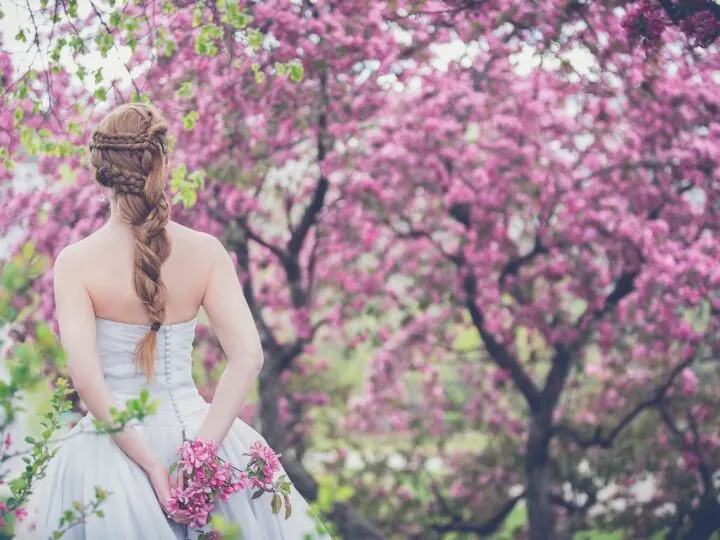 woman wearing wedding dress in front of tree full of blooms