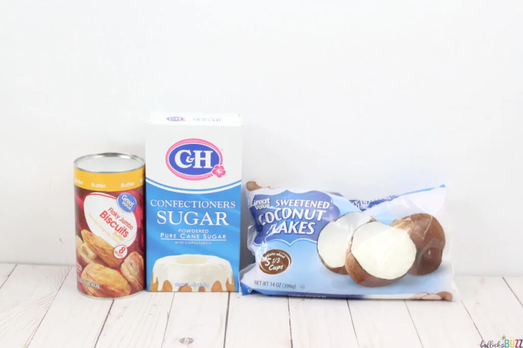 Canned biscuits, coconut flakes, and a package of confectioners sugar on a white background