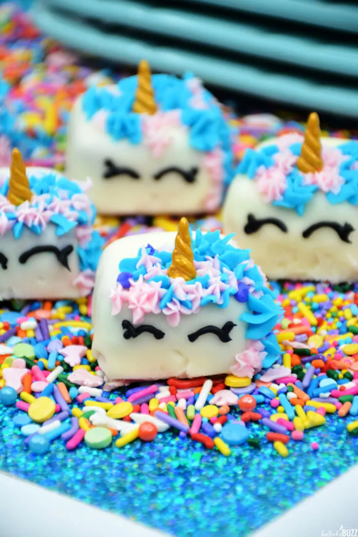 In this adorable Unicorn Petit Fours recipe, classic French Vanilla cake mix is transformed into miniature, multi-colored cakes that are covered with sweet vanilla icing, decorated with pink, purple and blue 'manes' and then crowned with a golden horn. #desserts #cakes #petitfours #unicorn