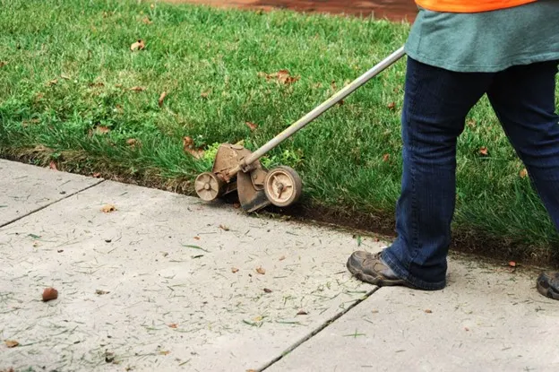 man trimming the yard with an edger