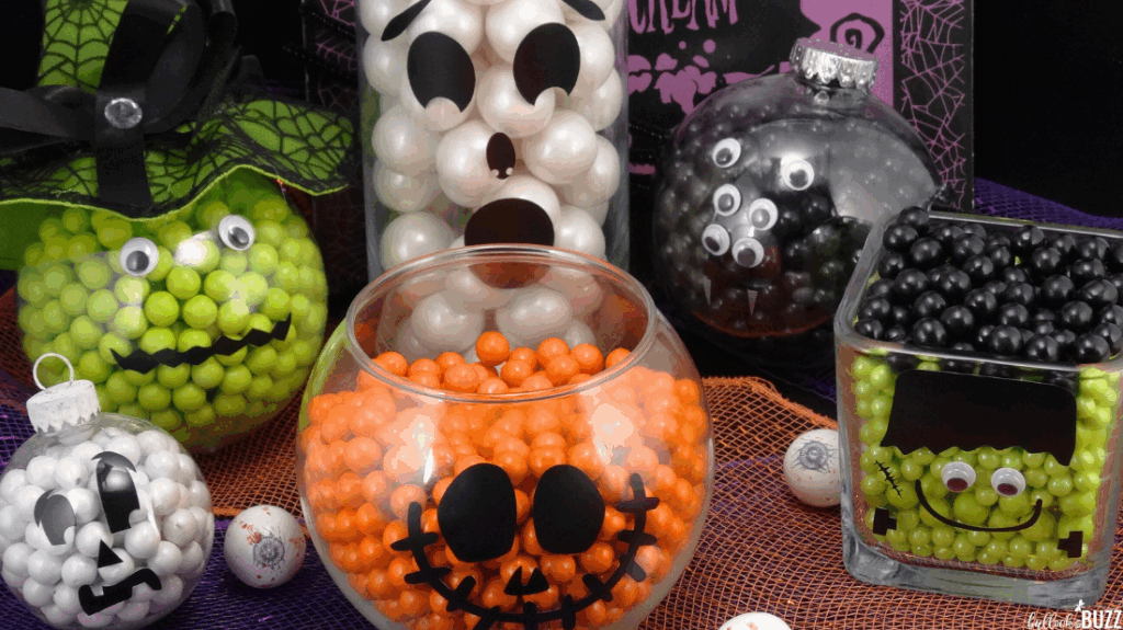 Candy jars on a table with candy filled Halloween ornaments
