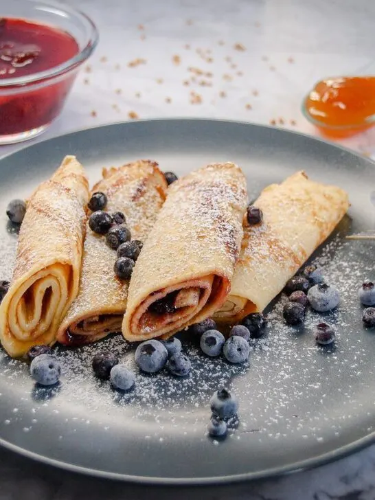 crepes topped with blueberries and powdered sugar