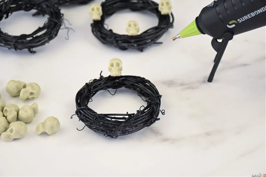 use hot glue to add skulls to DIY Halloween Napkin Rings