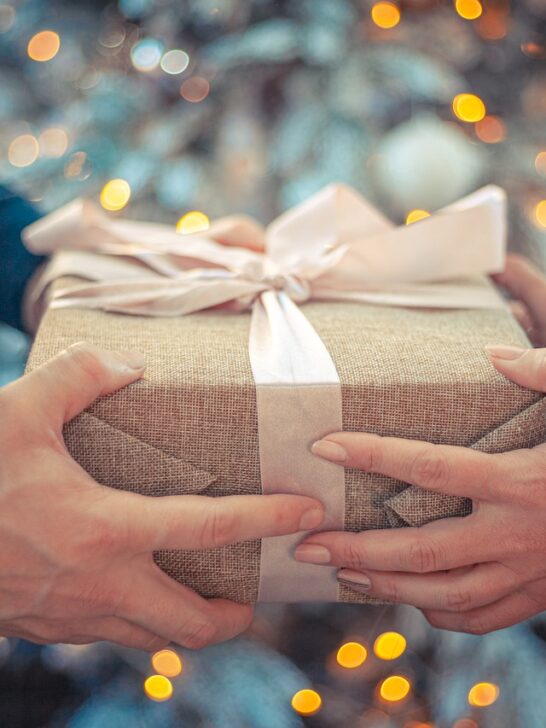 man handing a woman a gift from this list of gifts to buy for your partner