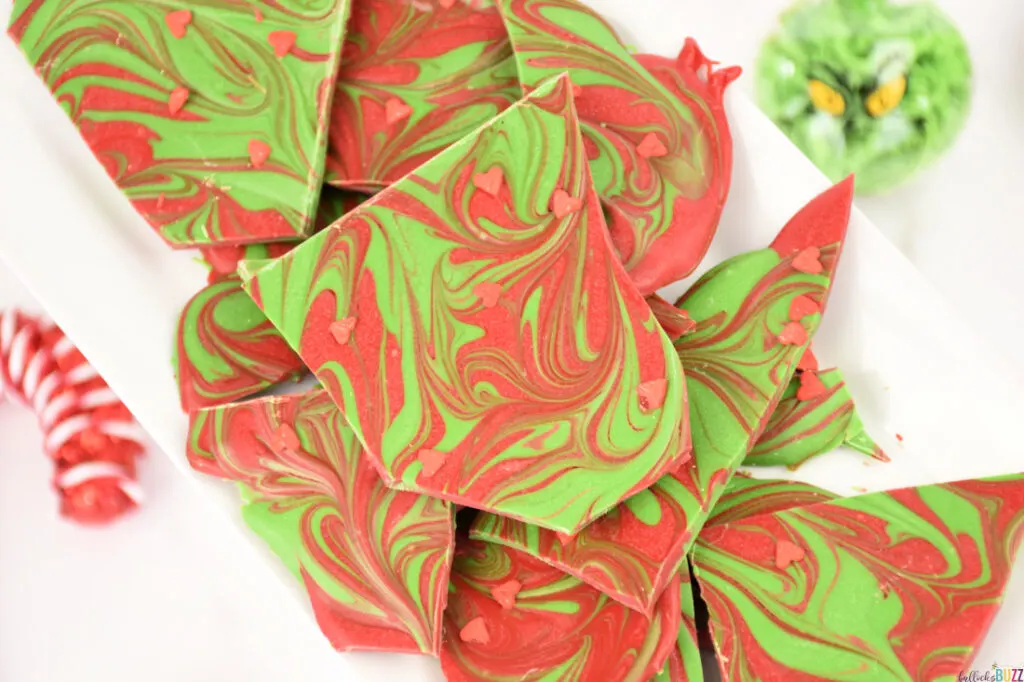 red and green candy bark on plate with Grinch ornament next to it