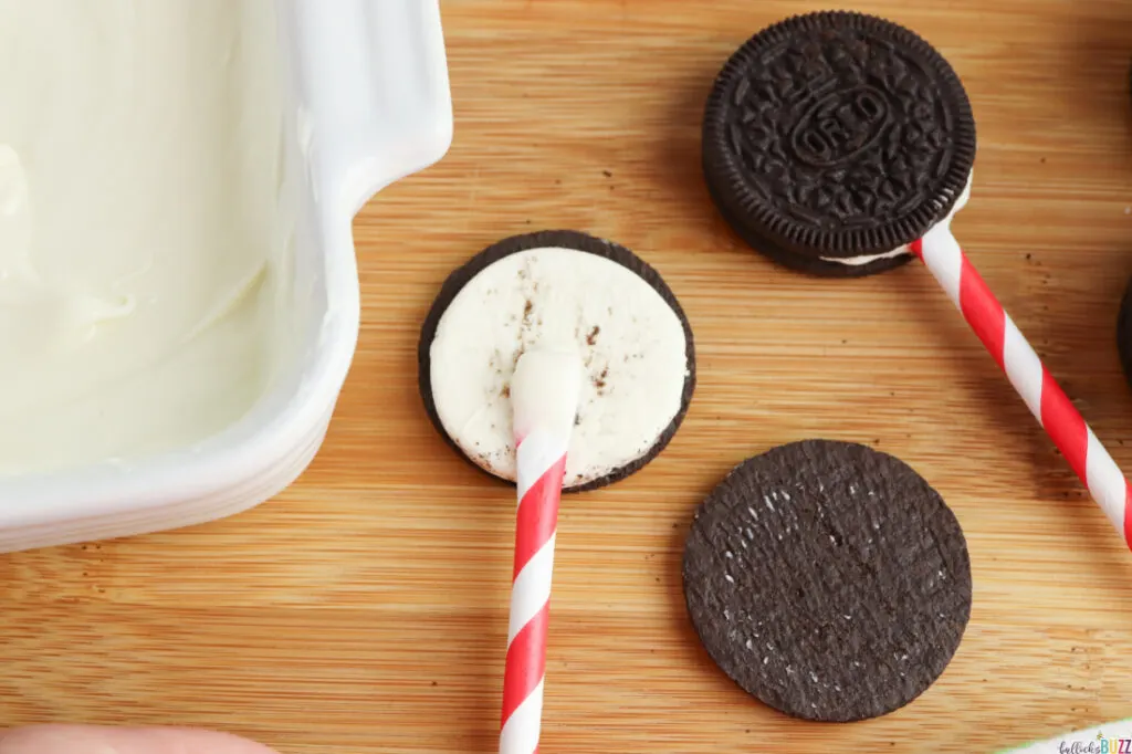 dip the flattened end of the straw in melted chocolate them place it on the open Oreo cookie