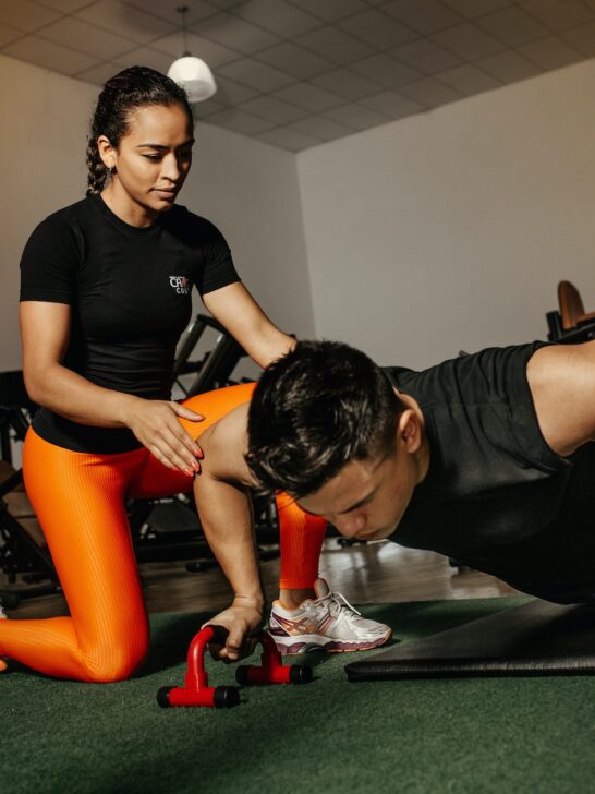 it takes dedication and hard work to become a certified personal trainer like this one who is kneeling next to her client working out