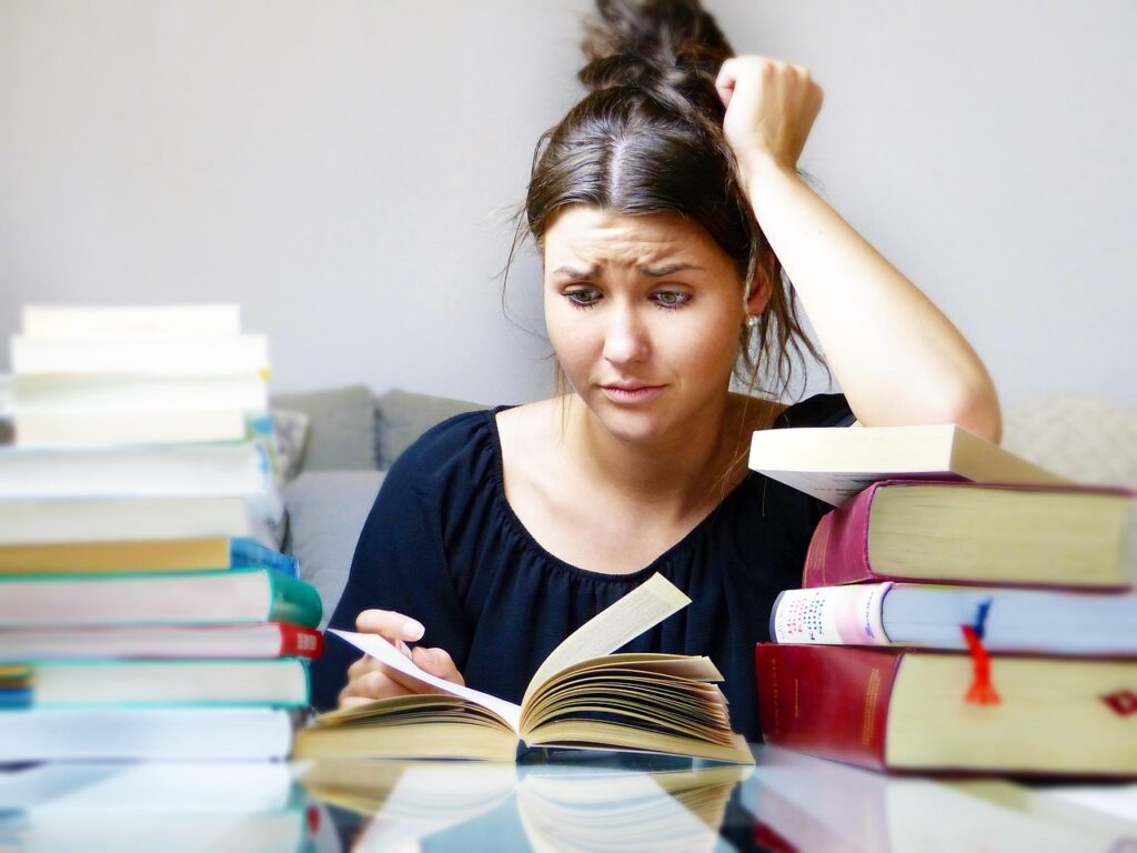 stressed-out college student studying while surrounded by books