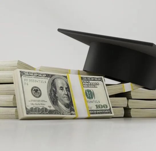 a stack of money with graduation cap representing student loan debt and refinancing student loans