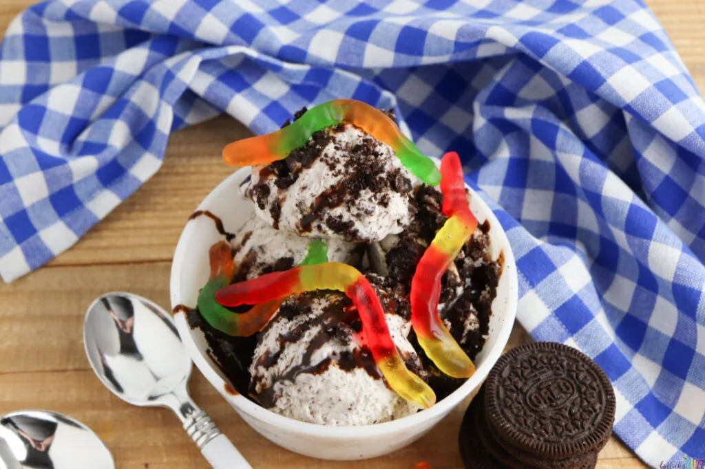 ice cream sundae in a bowl with a stack of Oreos and a spoon on a wood table