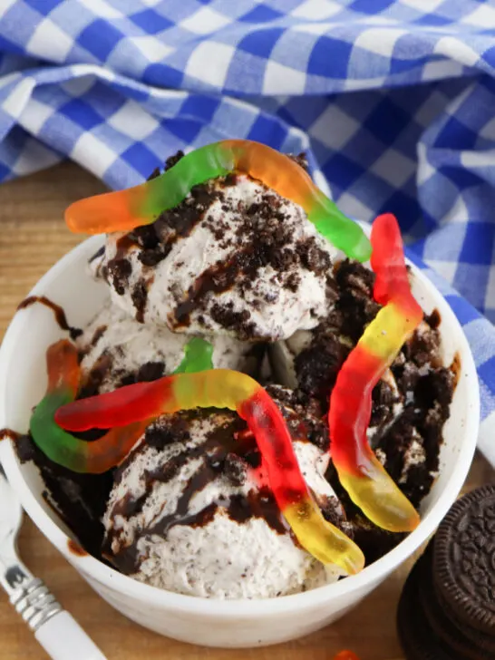 Easy dessert recipe with cookie ice cream topped with cookie crumbs, fudge and gummy worms