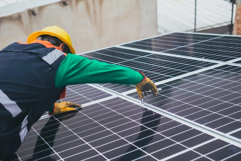 man installing solar panels on a roof