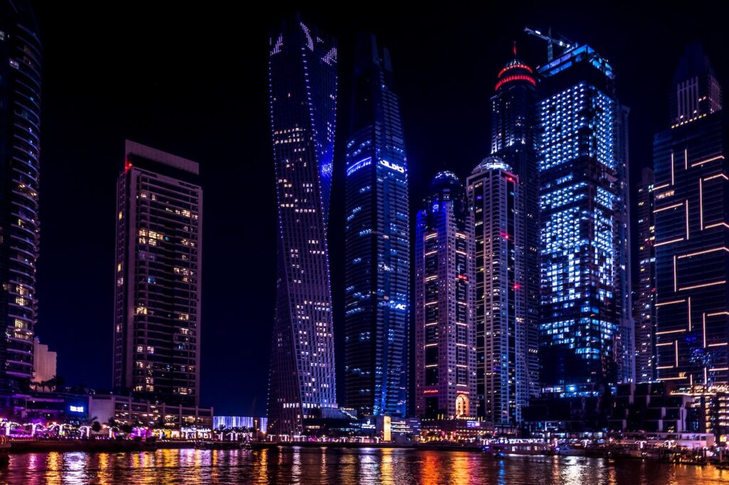 city buildings by the water lit up at night showing possible real estate in Dubai