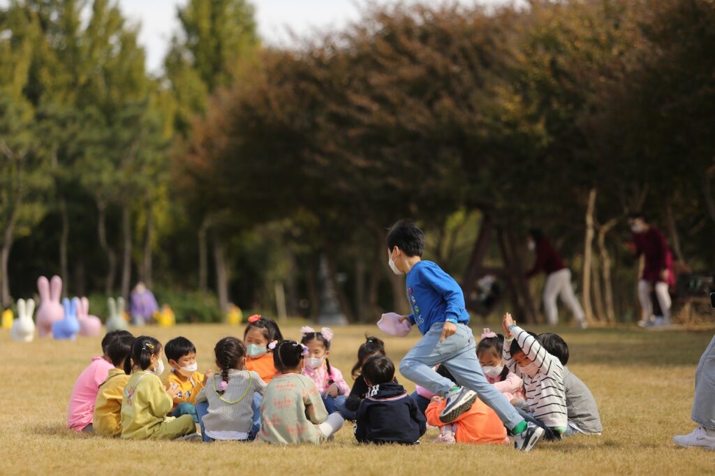 kids playing a game in the park as parents watch while using ways to keep your kids safe when playing outside