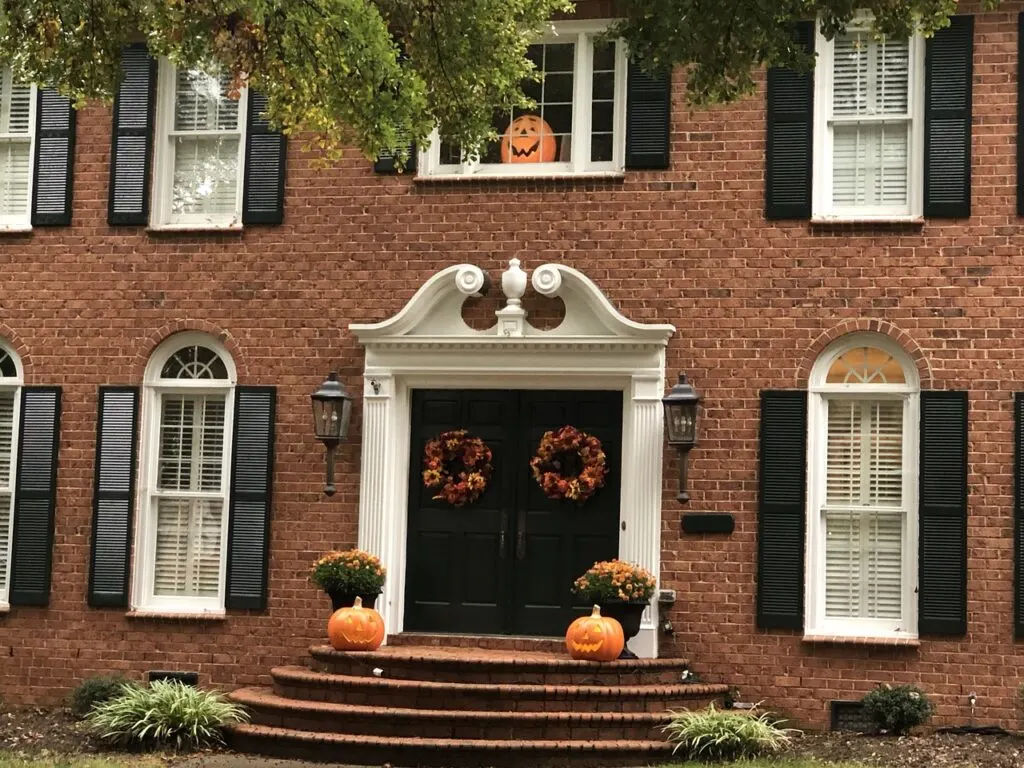 pumpkins, fall flowers and wreaths are used as autumn decor ideas on the front porch of this hiome