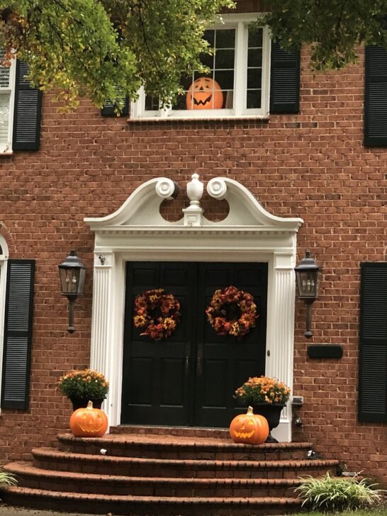 pumpkins, fall flowers and wreaths are used as autumn decor ideas on the front porch of this home