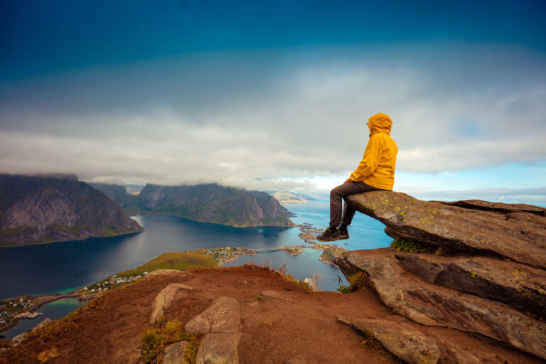 Male tourist sitting on the cliff. Beautiful mountain landscape
