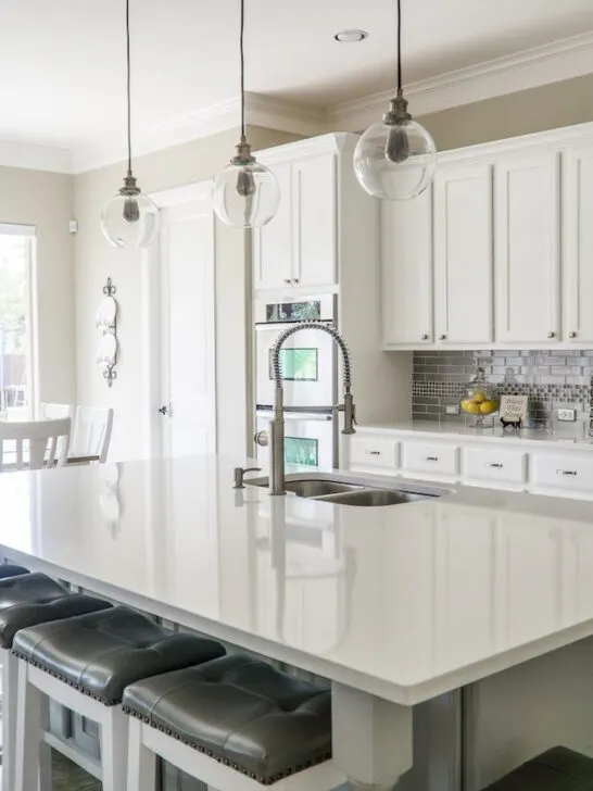 there are a lot of things to consider when choosing quartz countertops like the ones in this white kitchen