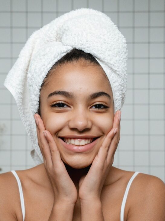 woman with her hair in a towel and gorgeous skin she got by using simple summer skincare tips