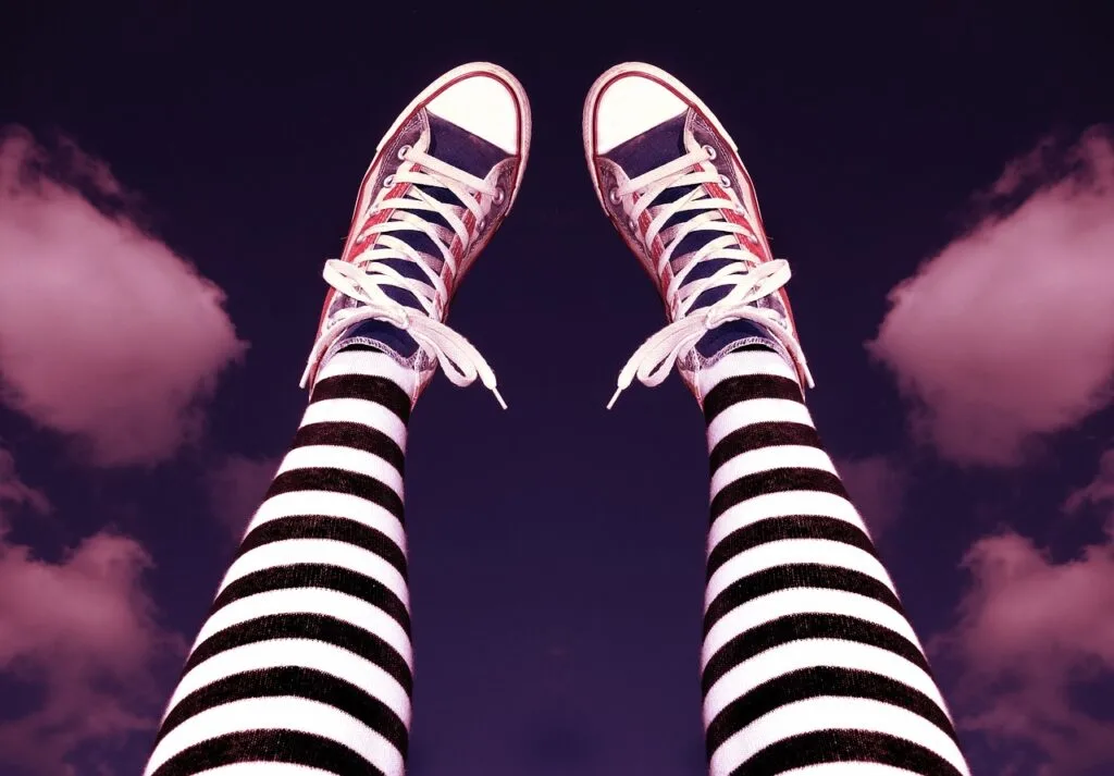 person's legs showing the best designer tights with black and white stripes and Converse shoes