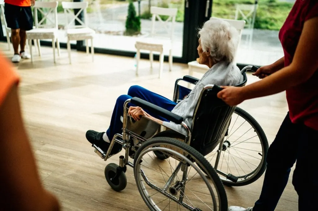 nurse pushing elderly woman in a wheelchair showing the importance of staff involvement when choosing the right nursing home