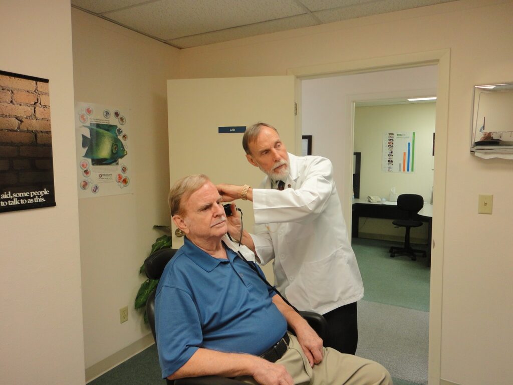 a doctor fitting a man with a hearing aid