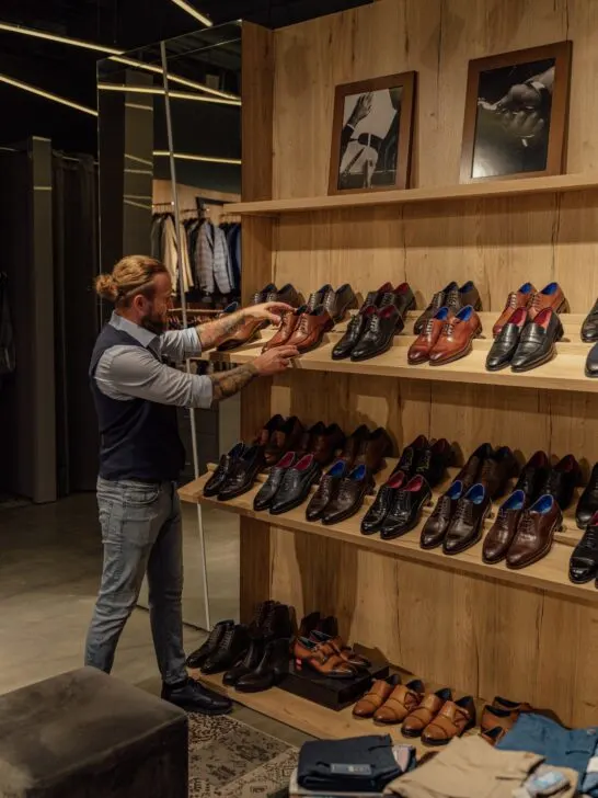 a variety of men's shoes on racks in a store
