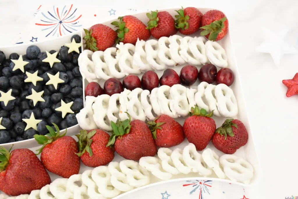 strawberries, cherries and white yogurt covered pretzels make up the stripes of the flag on this American Flag Fruit Tray