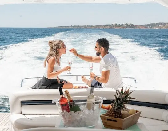 man feeding a woman a strawberry on the back of a boat during their yachting holiday