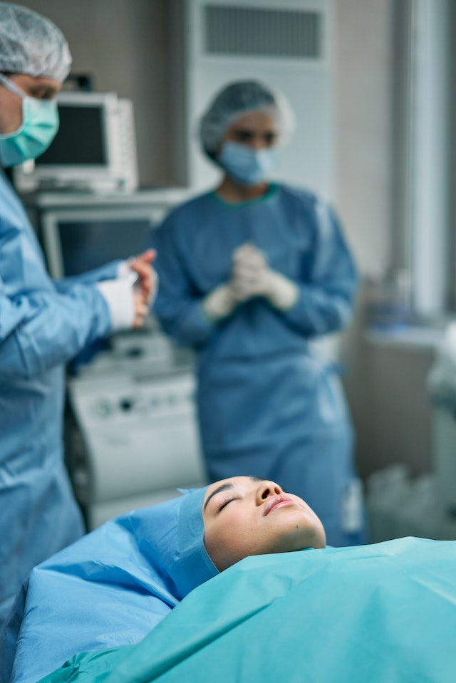 unconscious patient prepped for surgery as doctors prepare for facelift procedure