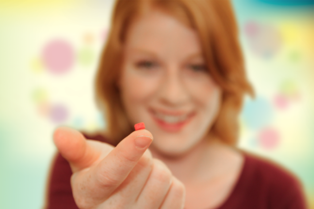 woman holding a superior source vitamin on tip of her finger to show how tiny the pills are