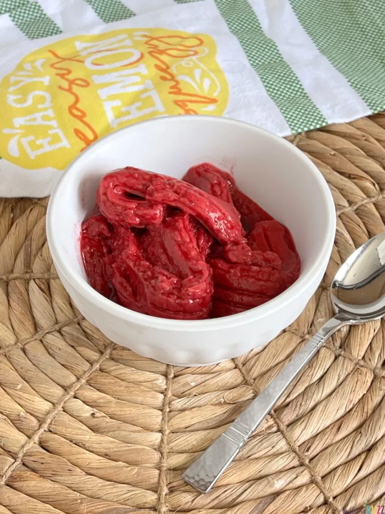 bowl of raspberry sorbet with a spoon laying next to it