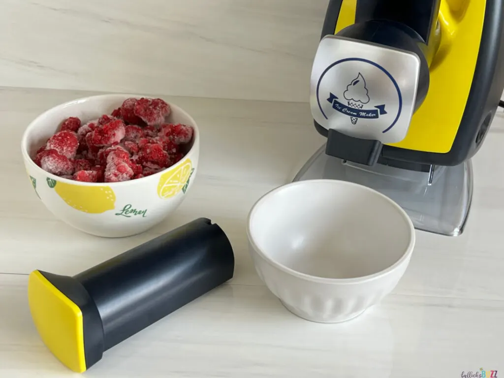 bowl of frozen raspberries sitting next to the sorbet maker