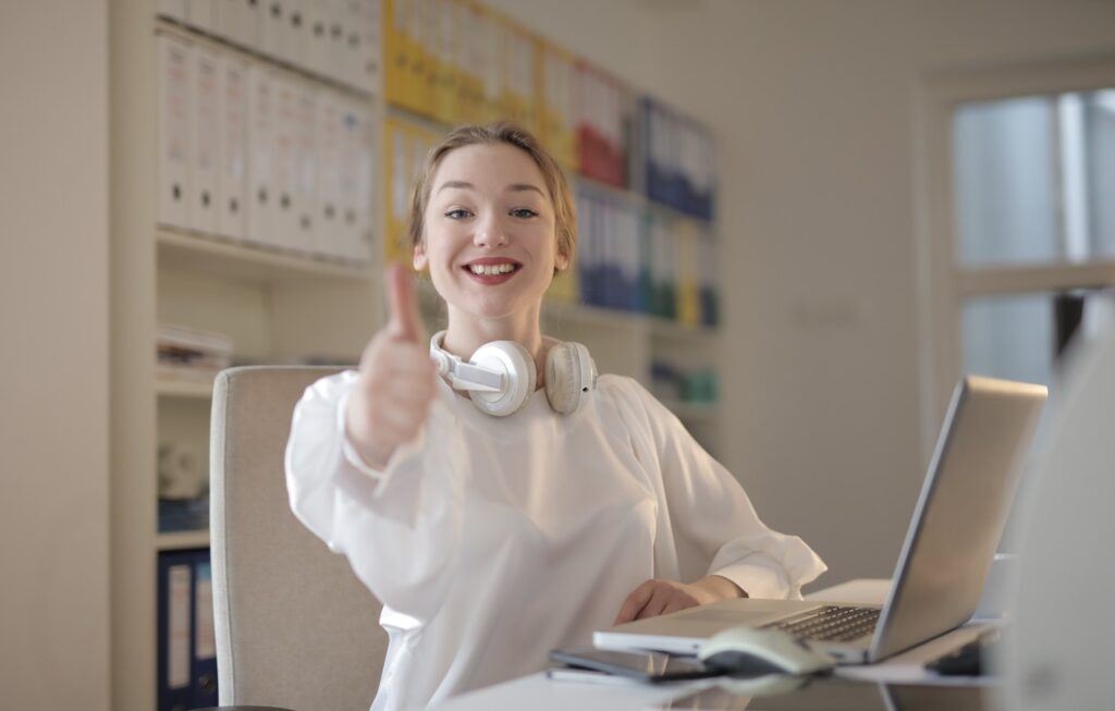 woman working at a desk giving the thumbs up sign