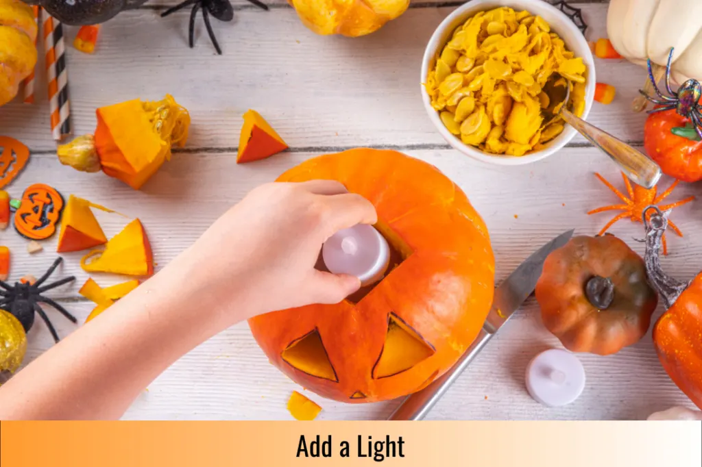 person adding a battery operated tea light to the finished jack o lantern