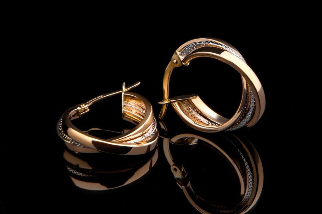 Gold and diamond loop earrings on a black background. There are lots of things to consider when choosing the best earrings for you.