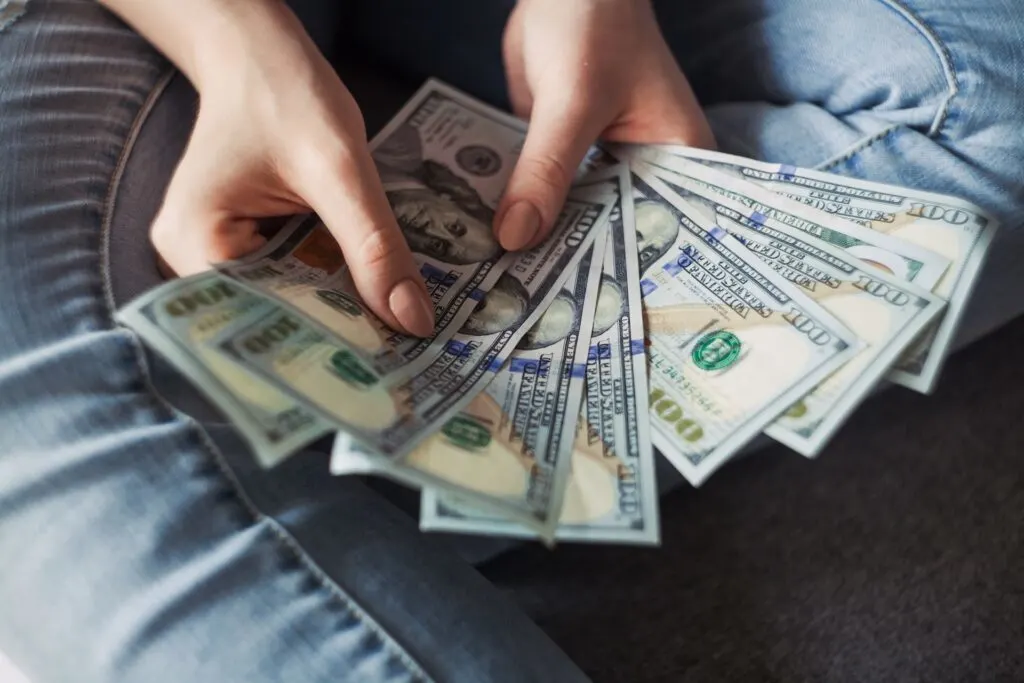 person holding a fan of money after learning about the process of borrowing money