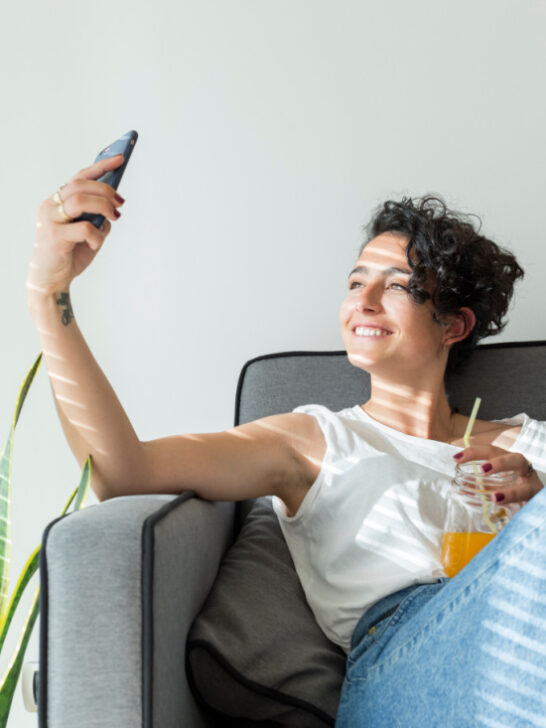 smiling woman sitting on the couch taking the perfect selfie