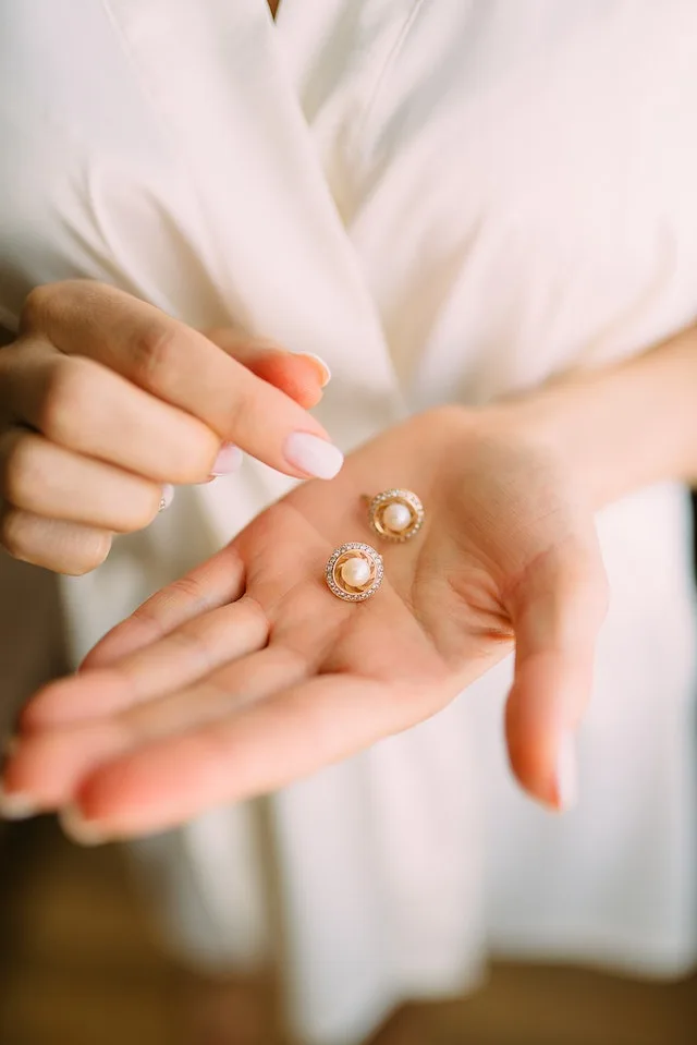 Woman holding pearl and diamond earrings. Considering the occasion is another thing to think about when looking for the best earrings for you.