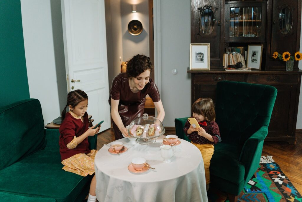 a woman serving snacks to two young children as their au pair