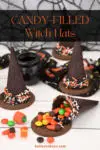 Candy-Filled Witch Hats laid out on a white table with one of the witch hats cracked open and candy spilling out