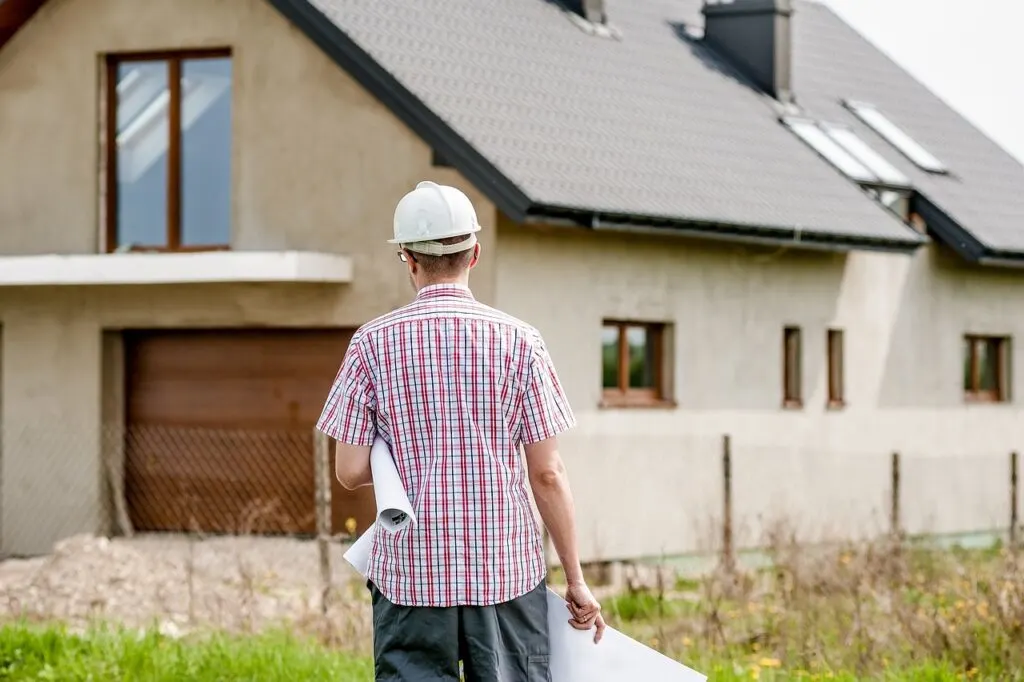 contractor waling towards a construction job carrying papers and plans