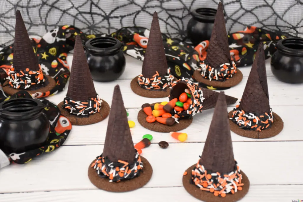 Halloween Candy-Filled Witch Hats on a table with one cracked open and the candy spilling out.