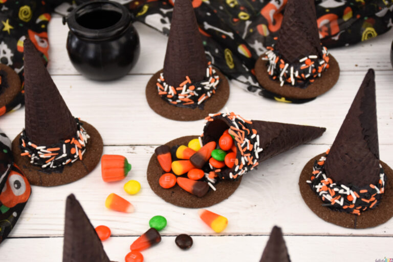 Overhead shot of finished ice cream cone witch hats with one broken open so candy is spilling out.