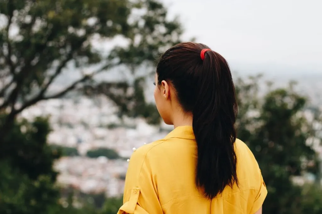 Woman in a yellow shirt wearing her brown hair in a ponytail.