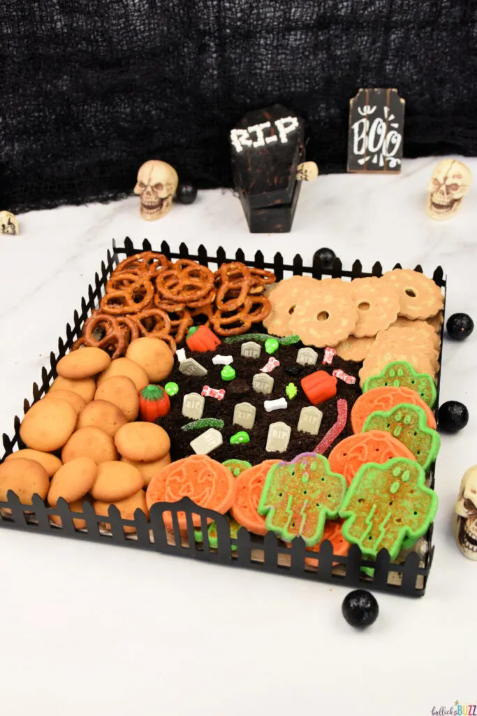 A spooktacular Graveyard Halloween Frosting Board adorned with cookies, pretzels, and other ghostly treats, ready for indulgence.