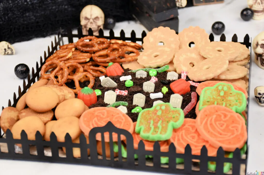 Halloween Frosting Board designed to look like a graveyard with cookies and pretzels surrounding a graveyard frosting dip.